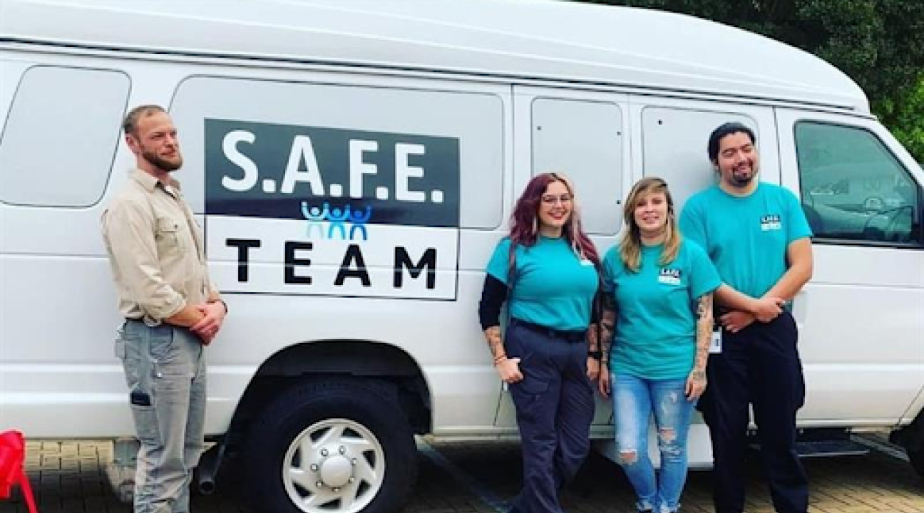 4 people posing outside in front of the SAFE Van